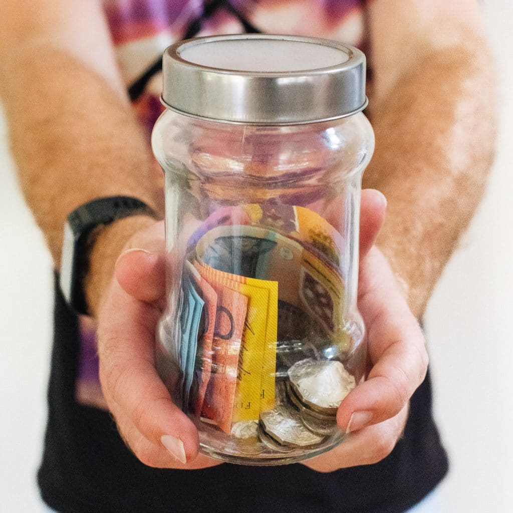 A man holding a jar of money, illustrating business advice services in Koroit, Victoria