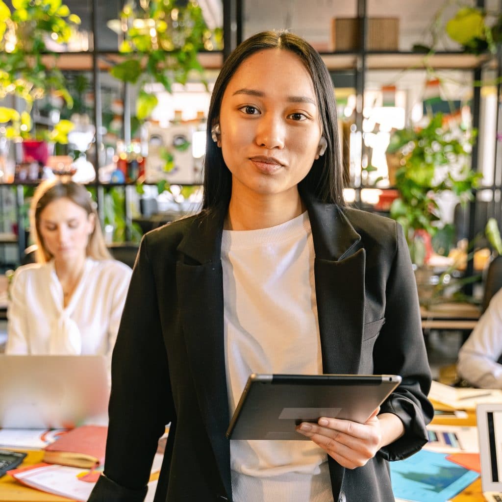 Asian woman at a workplace holding a device, illustrating the need to plan business structure in Victoria